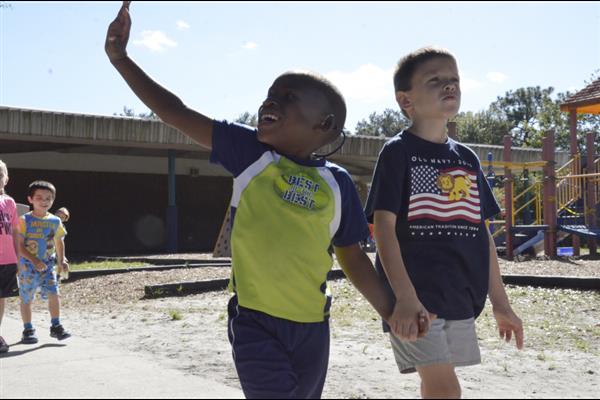two boys walking and waving at their friends